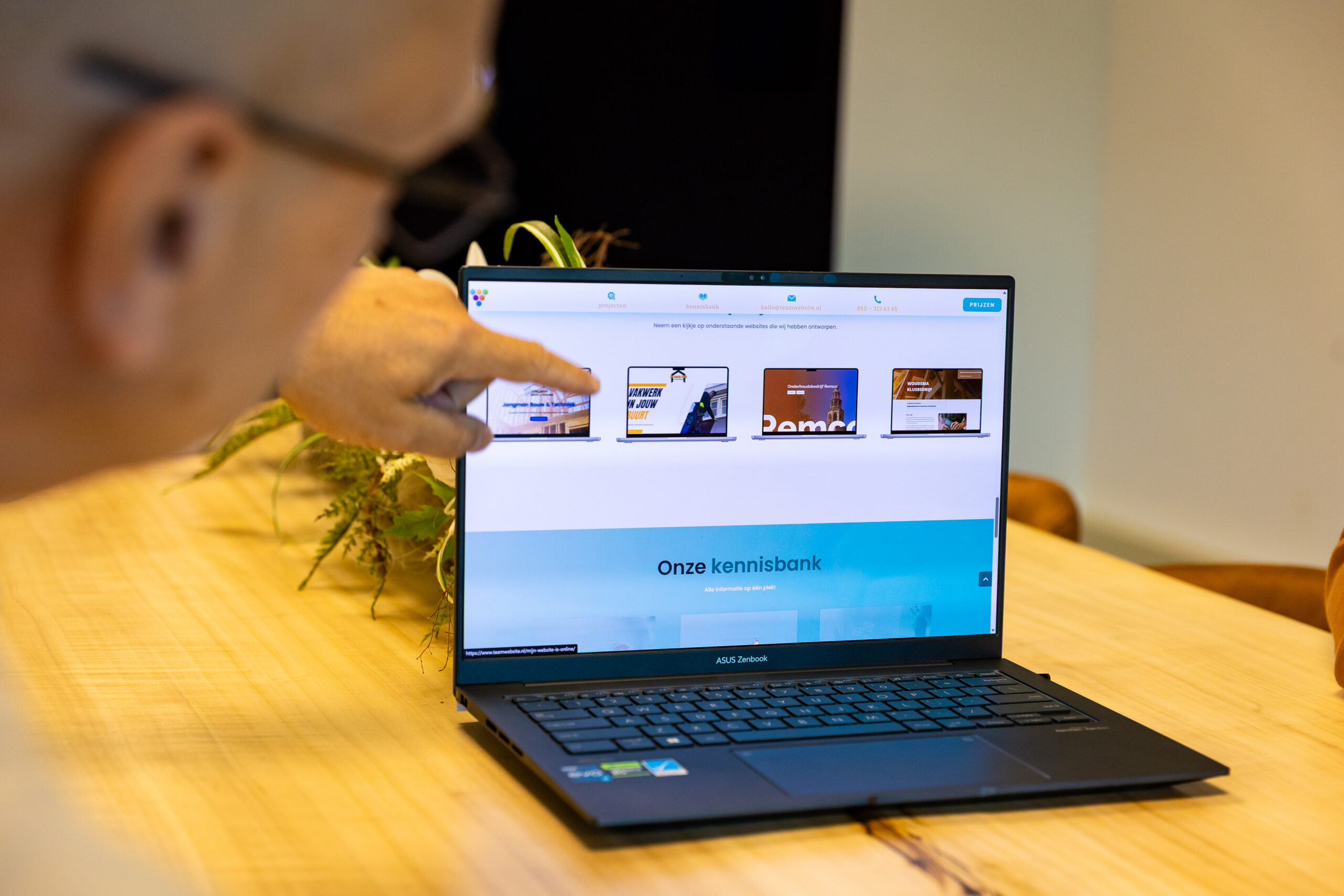 Medewerker van TEAM Website helpt een klant met het instellen van e-mail op de laptop.